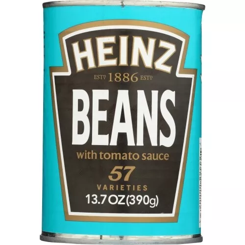 A close-up image of a Heinz Baked Beans can. The label is teal with a black shield-shaped design. It reads "Heinz Baked Beans," "57 varieties," and "13.7 oz (390g)." The Heinz logo and "Est 1886" are displayed at the top.