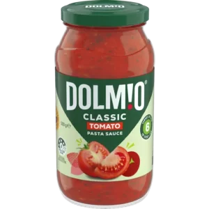 A jar of smooth Dolmio Smooth Tomato Sauce Jar with a green lid. The label shows "Dolmio" in bold white letters, with "Classic Tomato" underneath. There is an image of sliced tomatoes and fresh green leaves. The jar contains 500g of sauce and highlights a 6-ingredient recipe.
