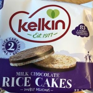 A package of Kelkin Rice Cakes Choco, labeled "Est. 1977." The package contains two rice cakes, one covered in milk chocolate. Nutritional information indicates 83 calories per rice cake. The design is white and purple with a heart-shaped logo.